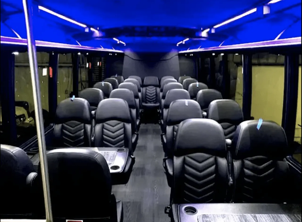 Ford Mini-Coach interior with passenger tables, cup holders and LED ceiling lighting for charter bus rental in Ballico, CA
