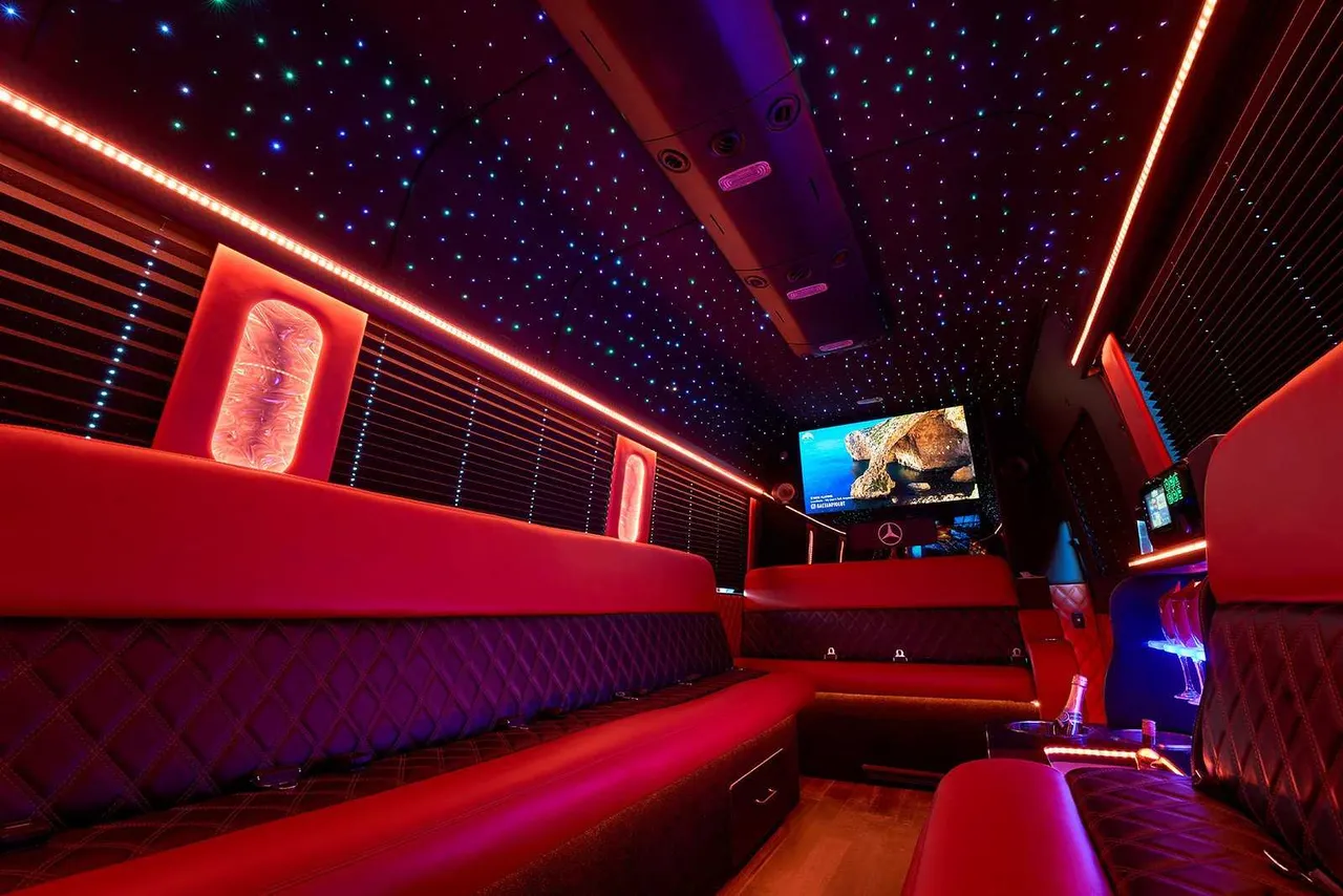 Limousine Bus interior with perimeter lounge seating, window shades and LED accent lighting, photo 2 for party bus rental