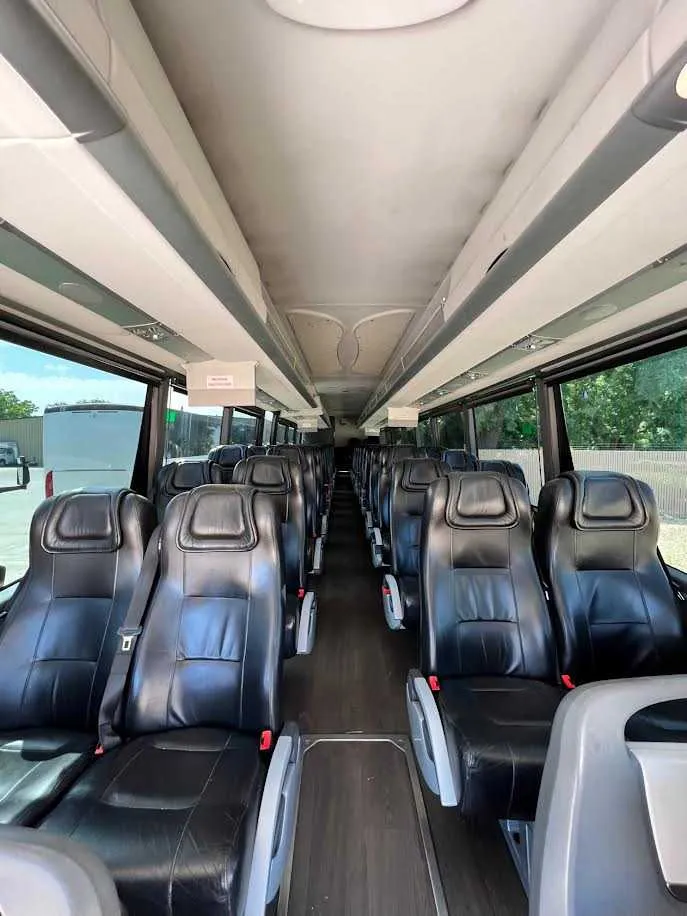 MCI Motorcoach interior with passenger seat belts and overhead parcel racks for charter bus rental in Dutch Flat, CA