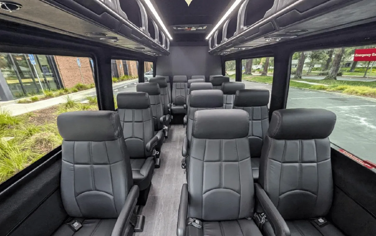 Mercedes-Benz Executive Sprinter interior with captain's chairs, wood-look flooring and overhead parcel racks for charter bus rental in San Jose, CA