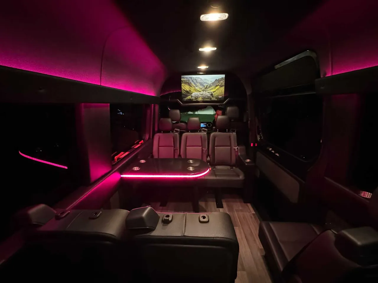 Mercedes-Benz Executive Sprinter interior with passenger tables, LED accent lighting and wood-look flooring for party bus rental