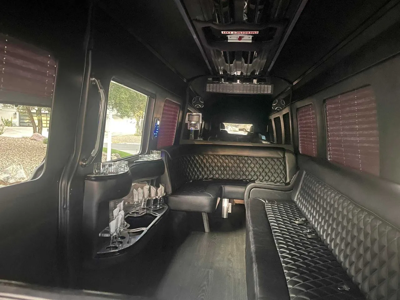 Mercedes Limo Sprinter interior with perimeter lounge seating, window shades and bar area for party bus rental