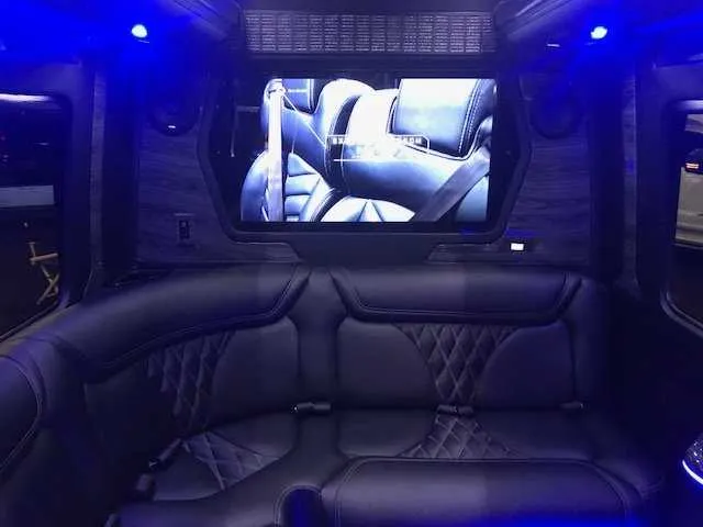 Mercedes-Benz Party Bus interior with sofa-style seating, LED accent lighting and TV screens for party bus rental in Mather, CA
