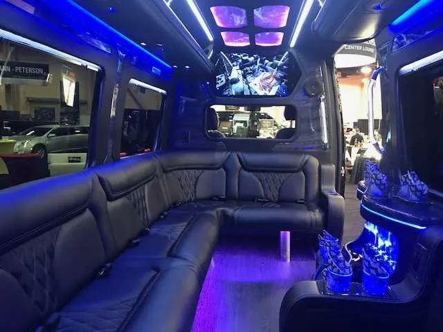 Mercedes-Benz Party Bus interior with sofa-style seating, LED accent lighting and LED ceiling lighting for party bus rental in Mather, CA