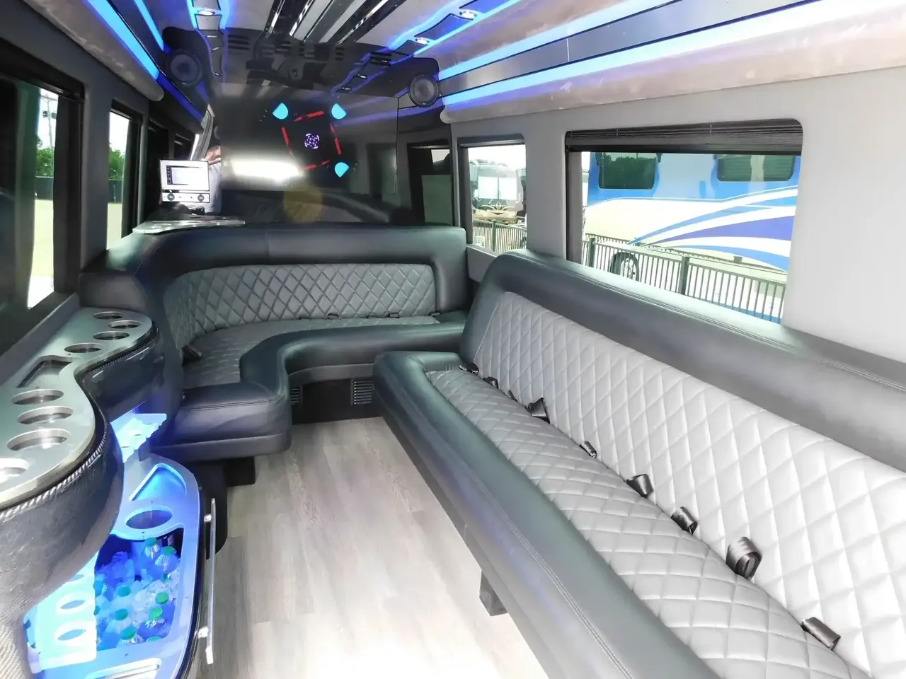 Mercedes-Benz Sprinter Limousine interior with perimeter lounge seating, LED accent lighting and wood-look flooring for party bus rental in Bedford, TX