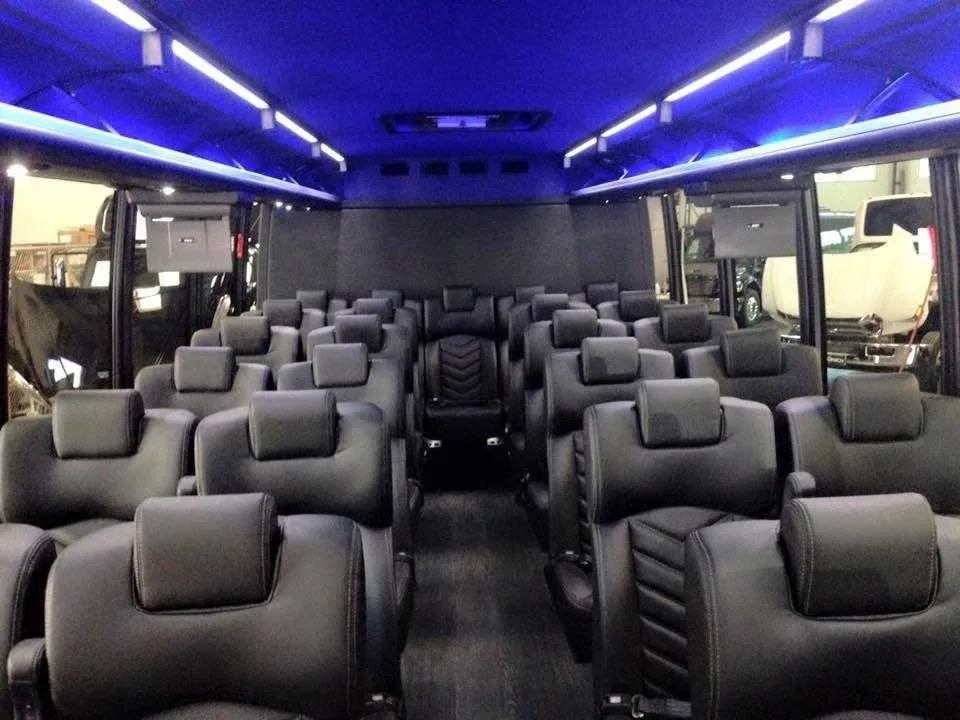 28 Passenger Mini Coach interior with airline-style seats, LED ceiling lighting and TV screens for charter bus rental in La Habra, CA