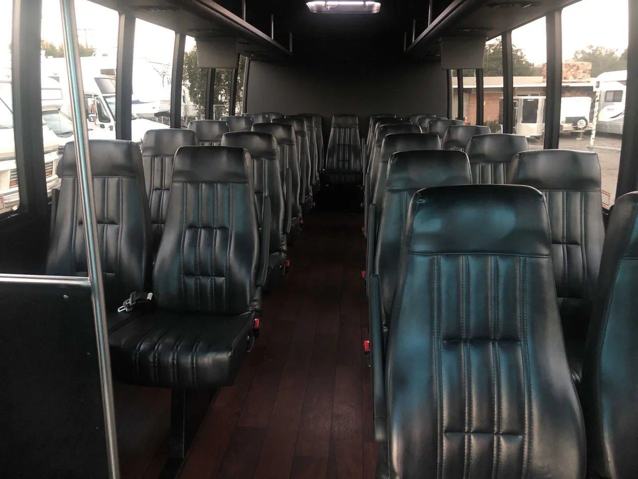 21 Passenger Mini Coach interior with airline-style seats, wood-look flooring and grab handles and rails for charter bus rental in San Diego County, CA