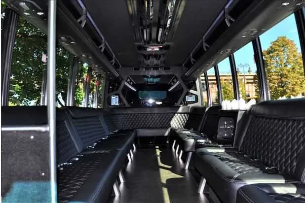 Mini Coach Limousine Bus interior with perimeter lounge seating and dance pole for party bus rental