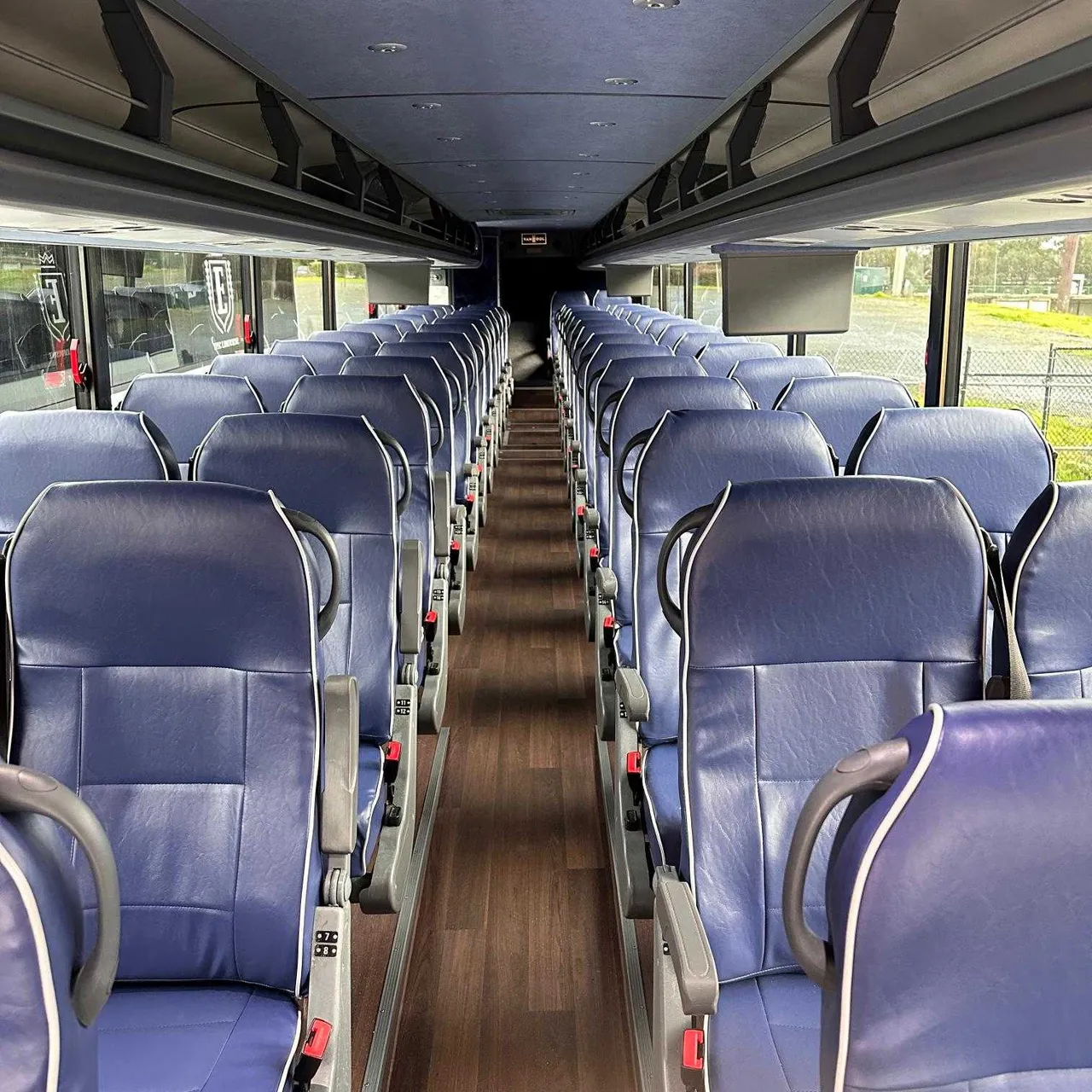 56 Passenger Motorcoach interior with passenger seat belts and overhead parcel racks for charter bus rental in Daly City, CA