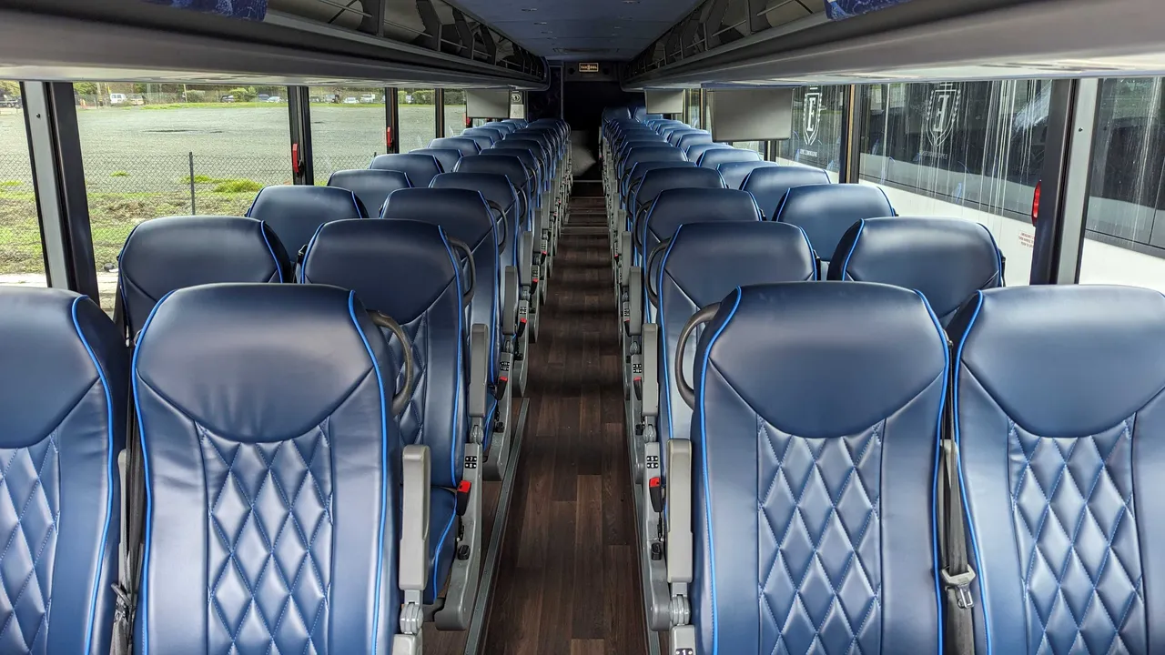56 Passenger Motorcoach interior with passenger seat belts and overhead parcel racks, photo 3 for charter bus rental in Daly City, CA