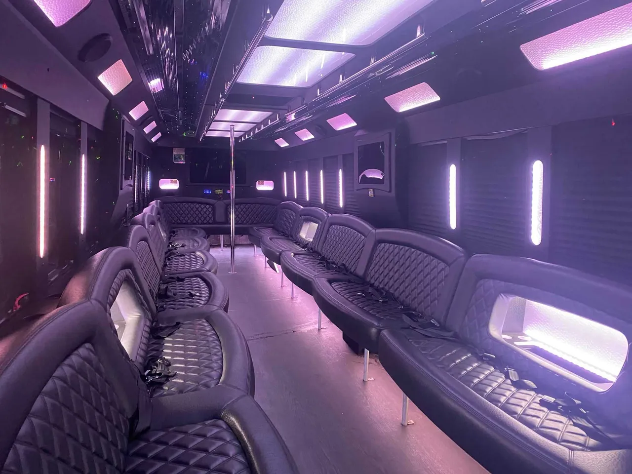 25 Passenger Party Bus interior with perimeter lounge seating, LED accent lighting and LED ceiling lighting for party bus rental in Ozone Park, NY