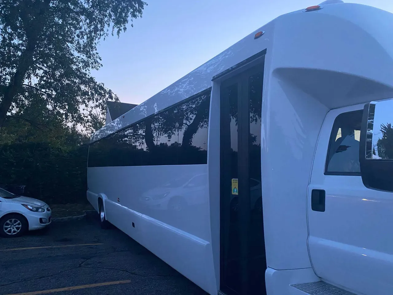 White 25 Passenger Party Bus exterior with tinted windows for party bus rental in Ozone Park, NY