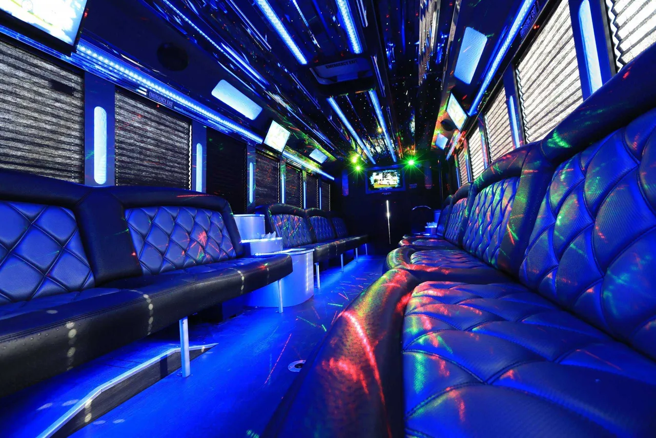 30 Passenger Party Bus interior with perimeter lounge seating, window shades and LED accent lighting for party bus rental in Dallas, TX