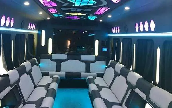 Inside of the Party Bus White, showing perimeter lounge seating, window shades and LED accent lighting