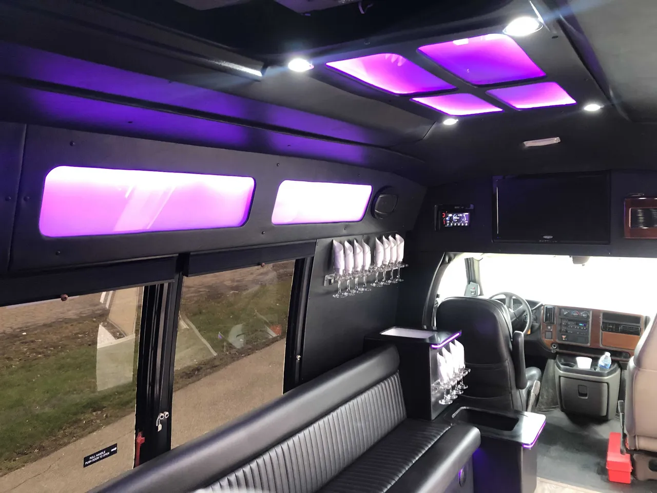 Small Party Bus interior with perimeter lounge seating, LED ceiling lighting and glassware holders for party bus rental in Pittsburgh, PA